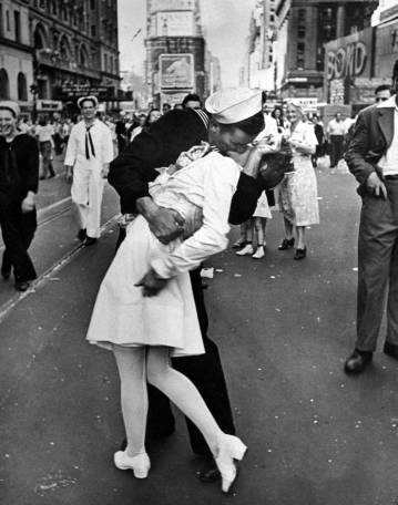 Caption from the August 27, 1945, issue of LIFE. "In the middle of New York's Times Square a white-clad girl clutches her purse and skirt as an uninhibited sailor plants his lips squarely on hers."